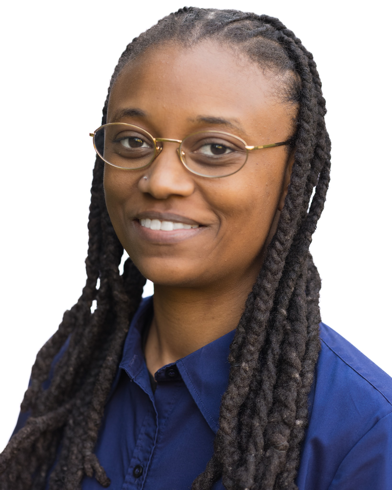 Professional headshot of a smiling woman with long locs, wearing wire-rimmed glasses and a blue button-down shirt against a white background.