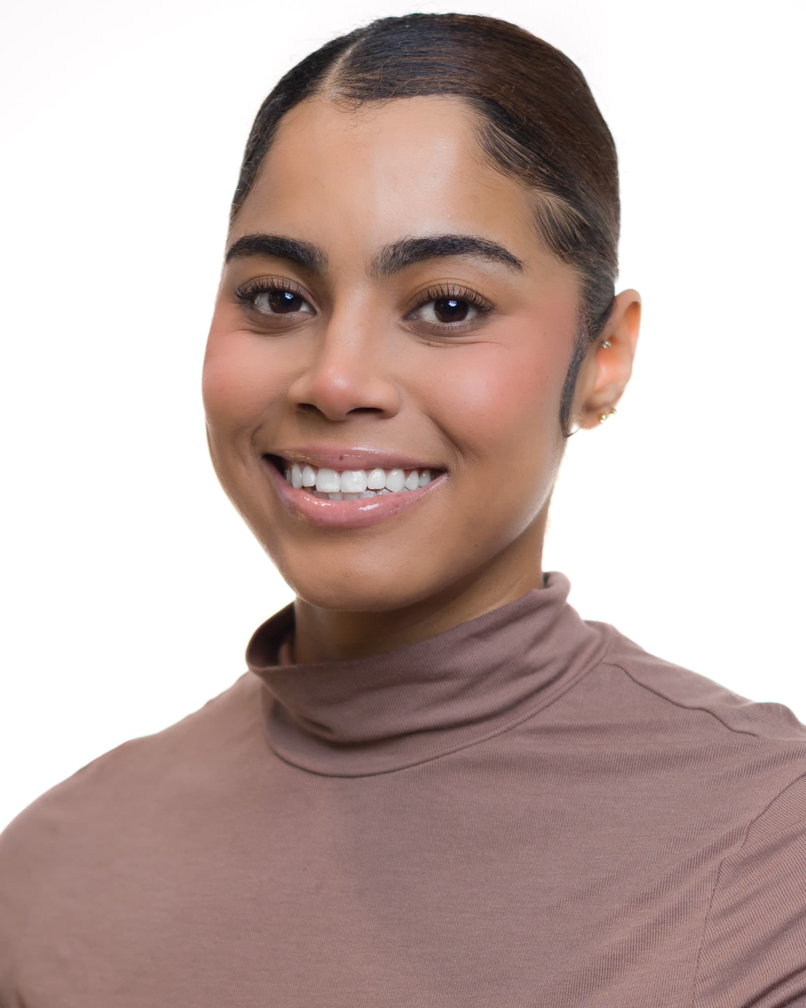 Professional headshot of a smiling woman with dark hair wearing a brown turtleneck, photographed by Fuentes Studio.